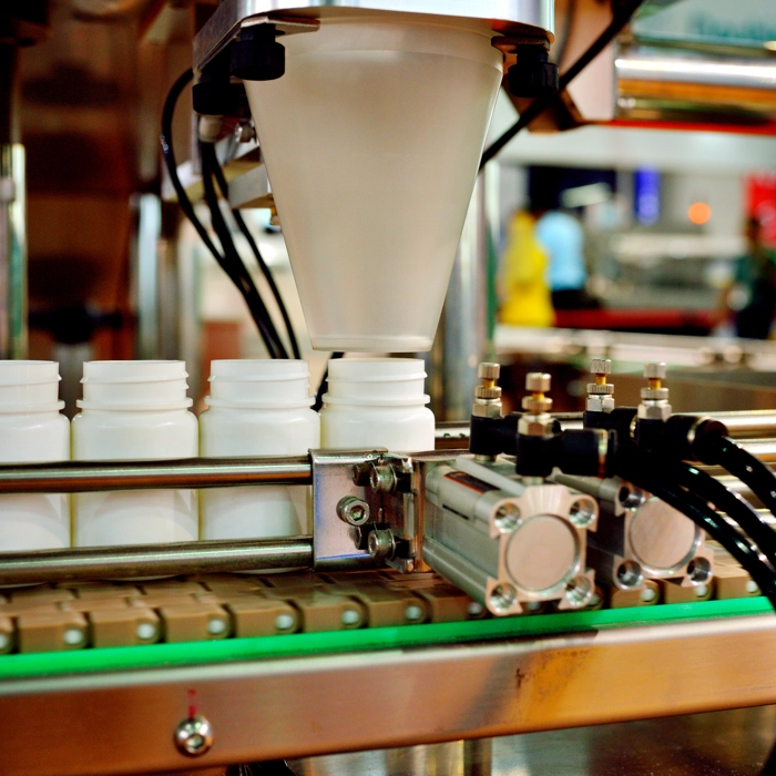 Machinery putting supplements into plastic white bottles Machinery putting supplements into plastic white bottles