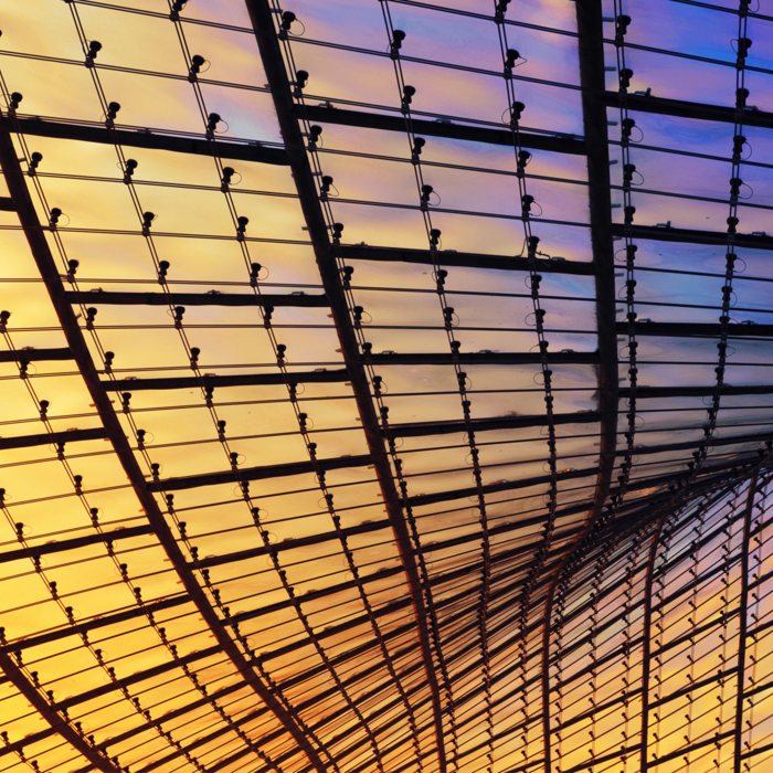 Curved glass and steel ceiling structure glowing with warm yellow and cool purple light. Curved glass and steel ceiling structure glowing with warm yellow and cool purple light.