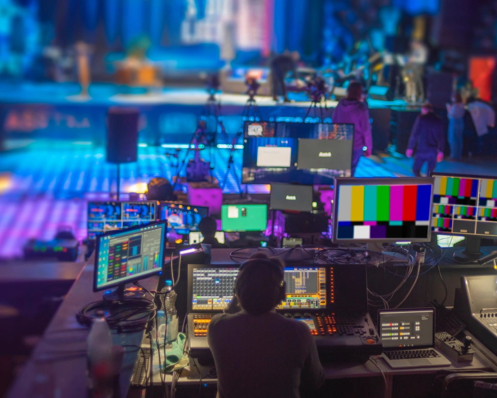 Person sitting behind video editing screens in live tv media studio Person sitting behind video editing screens in live tv media studio